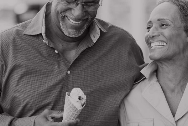 Older African American couple walking and smiling with ice cream in hand