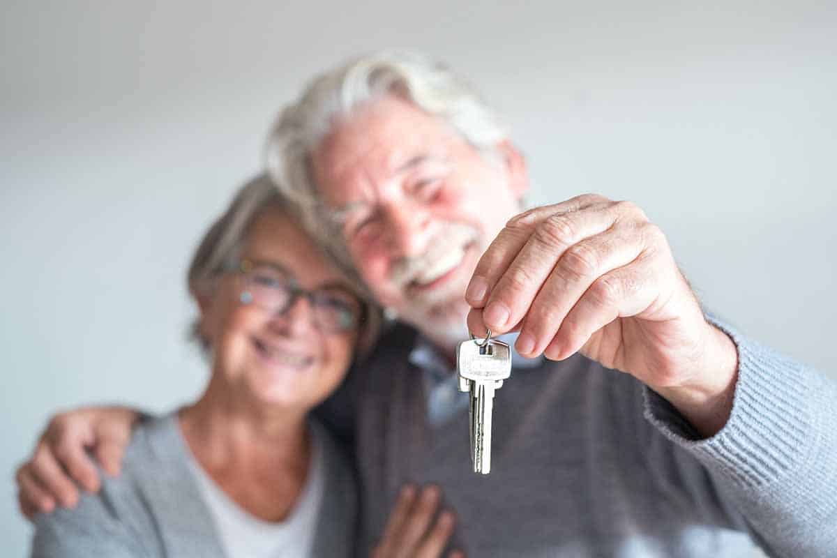 Happy older couple smiling and holding up a house key.